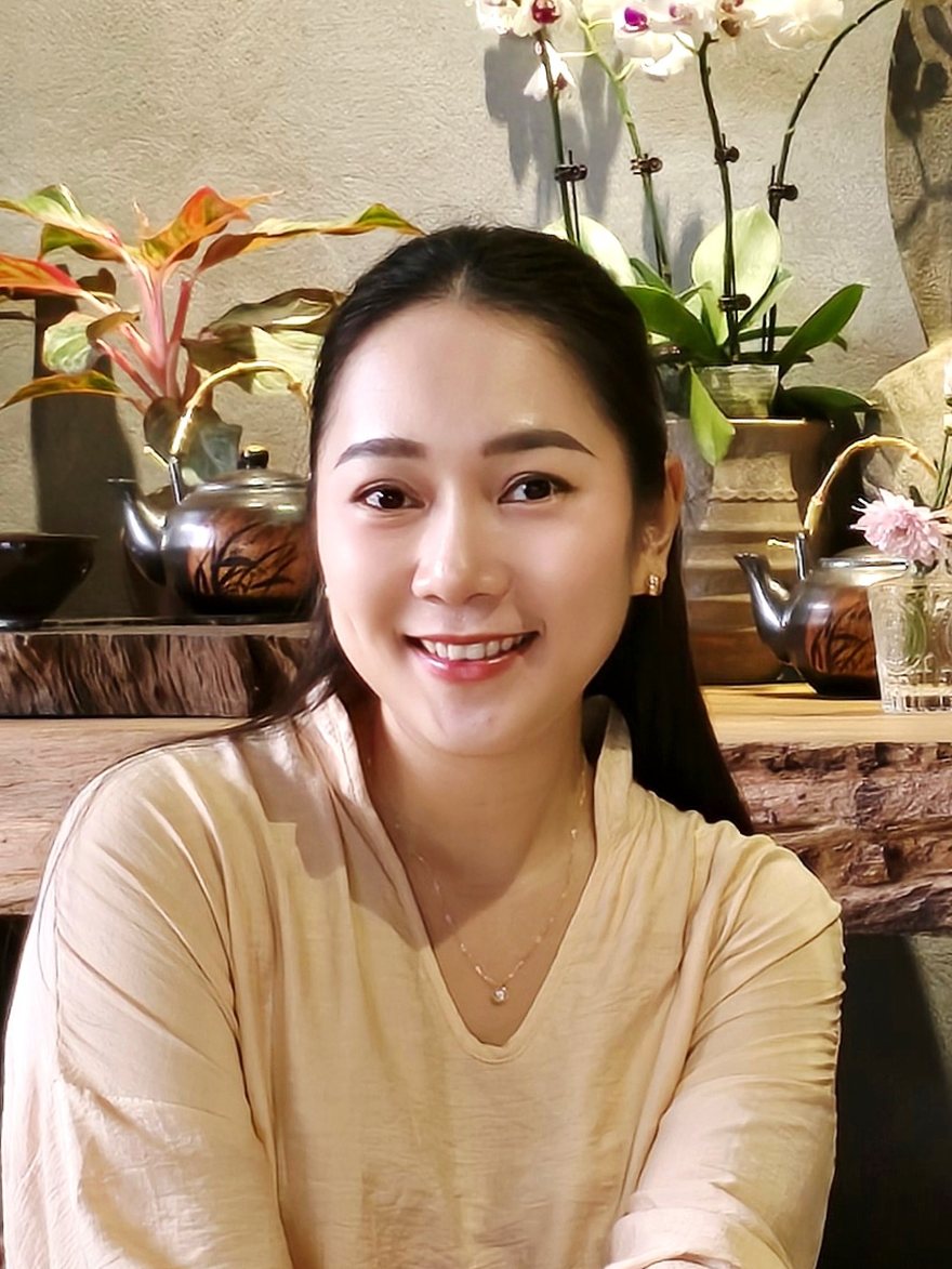 Chân dung Grace mỉm cười, phía sau là ấm trà, chậu cây và hoa lan